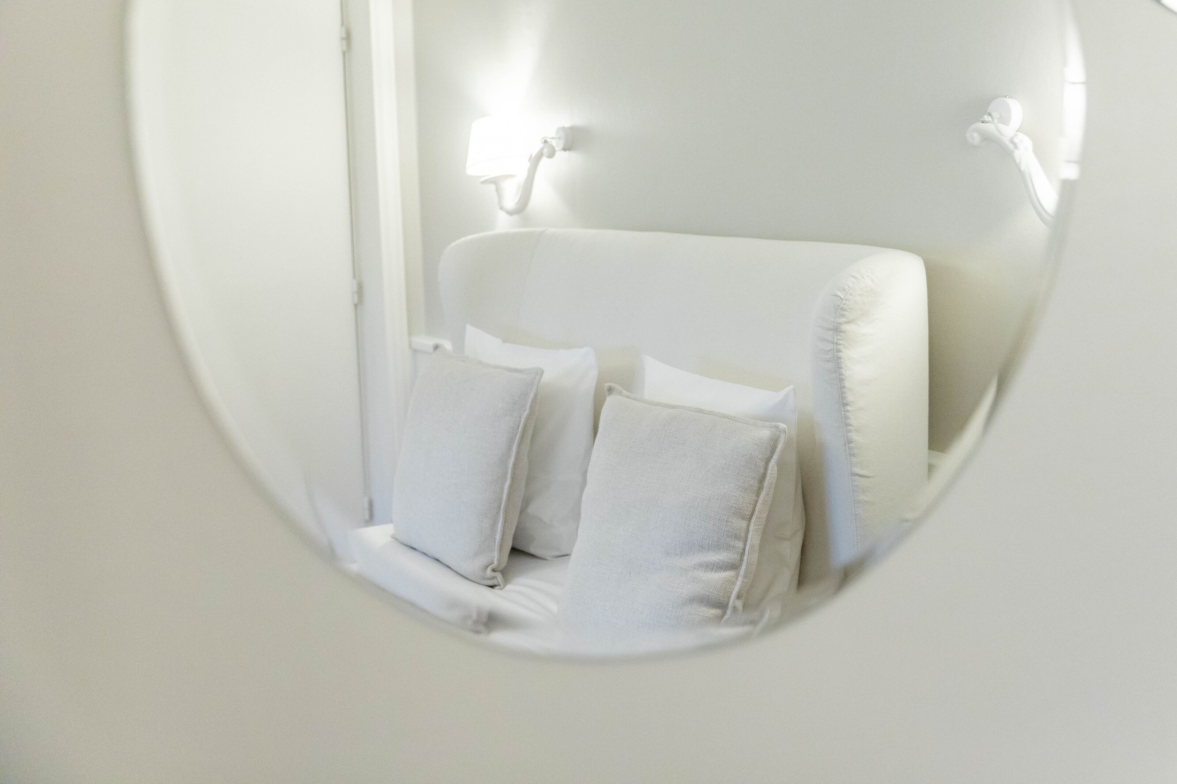 A white room with a bed, two bedside lamps, and two pillows.