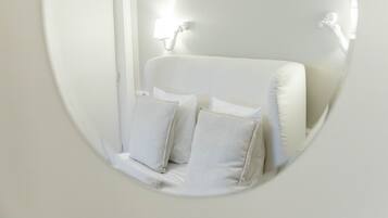 A white room with a bed, two bedside lamps, and two pillows.