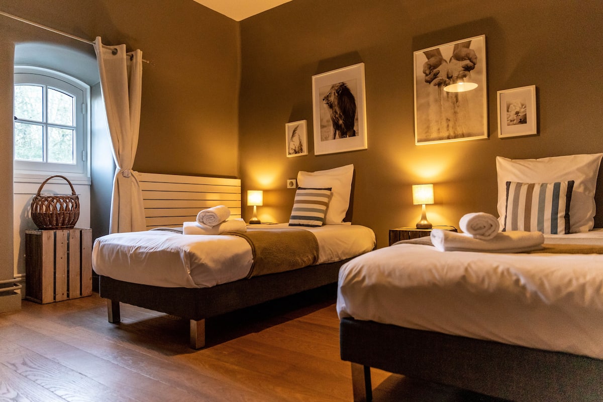 Una habitación de hotel con dos camas, una ventana con cortinas y obras de arte colgadas en la pared.