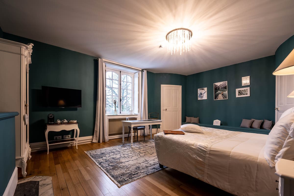 Un dormitorio con una cama, un escritorio, una silla, un televisor y una ventana.