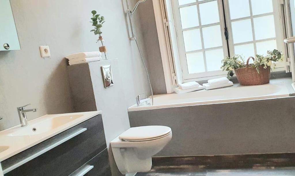 A bathroom with a bathtub, a toilet, a sink, and a window with a view.