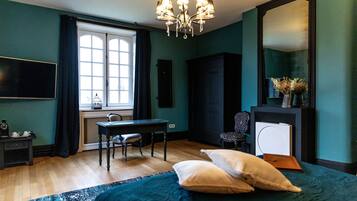 Un dormitorio con cama, escritorio, silla, televisor, espejo y ventana con cortinas.