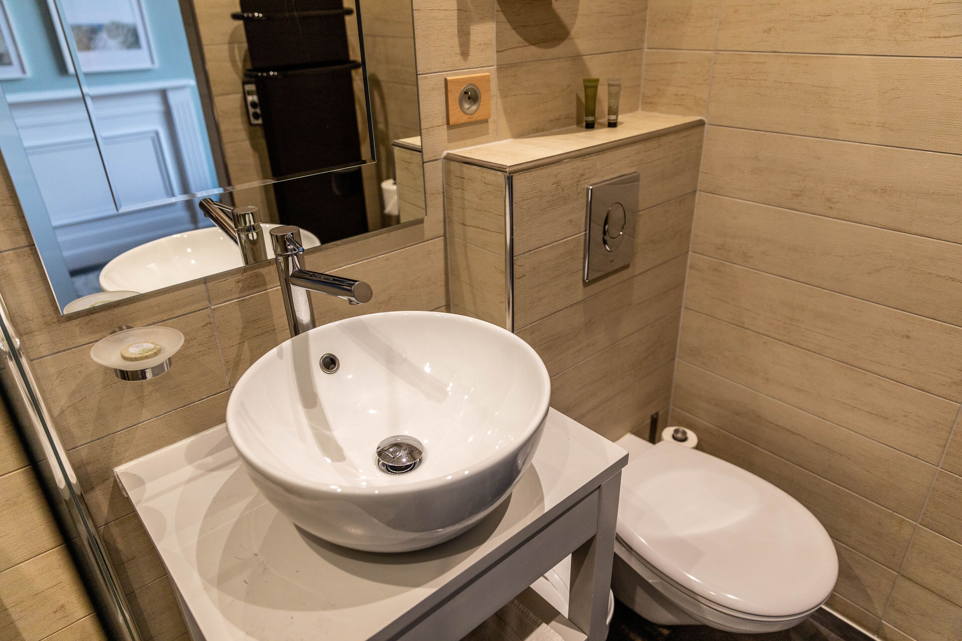 Et moderne badeværelse med en hvid vask, et toilet og et spejl over vasken.