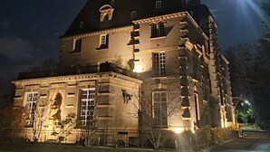 A large, illuminated historic building with a prominent tower and multiple windows. - Ô Château (Hayange)