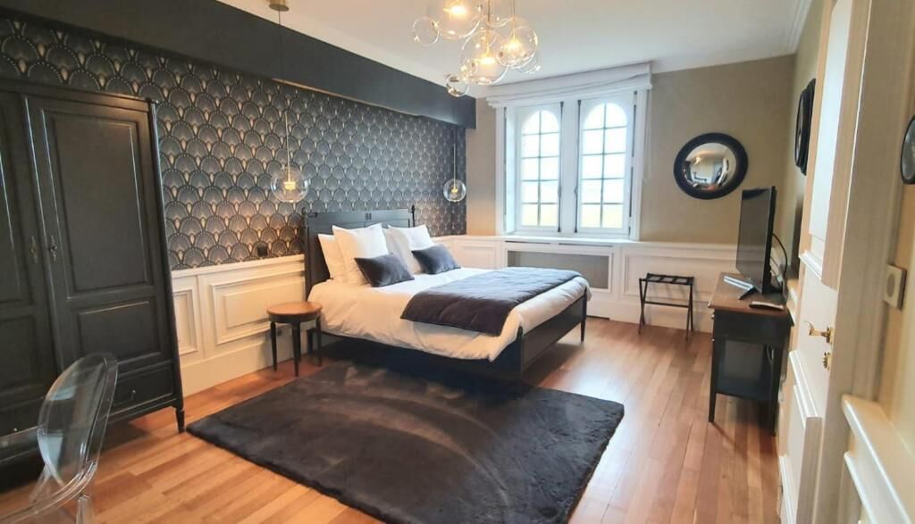 Un dormitorio con una cama, una ventana, un espejo y una araña.