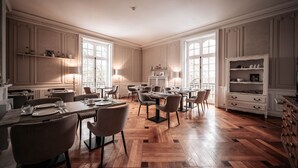 A spacious dining area with wooden parquet flooring, white paneled walls, and large windows allowing natural light. - Ô Château (Hayange)