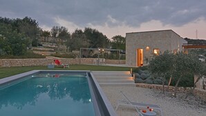 A modern outdoor pool area with a stone building, a pergola, and a well-maintained lawn. - Villa Gilda 5 1 in Avola (Avola)