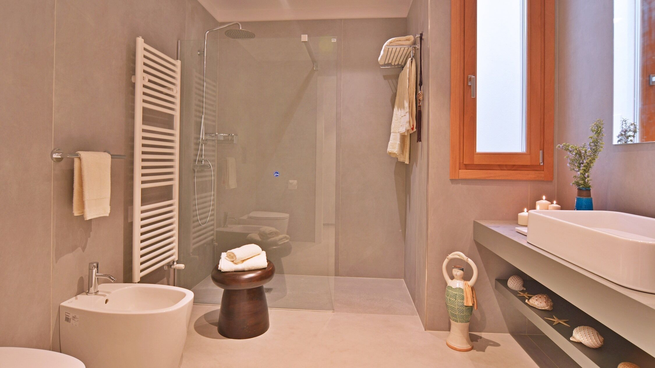 A modern bathroom with a shower, toilet, bidet, and vanity.