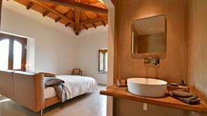 A bedroom with a large bed, a wooden ceiling, a built-in circular sink, and a mirror. - Villa Terre Normanne 13 (Castiglione di Sicilia)