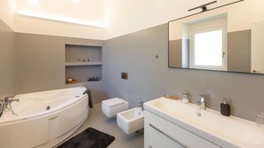 Ein modernes Badezimmer mit einer Badewanne, einem Waschbecken, einer Toilette und einem Waschtisch.