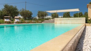 Ein klares Schwimmbecken mit Liegestühlen und einer überdachten Sitzgelegenheit.