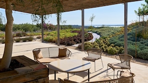 Un área de estar al aire libre techada con muebles de mimbre, una mesa y un hogar.
