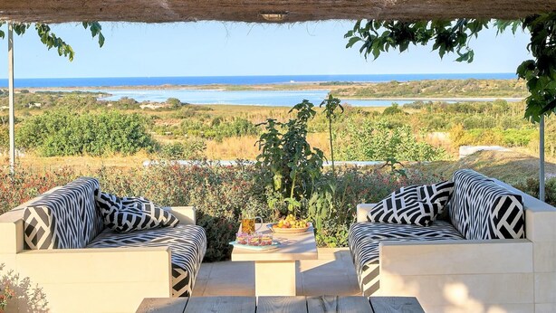 An outdoor seating area with two sofas and a table, overlooking a coastal landscape. - Villa Majoli 9 in Noto (Noto)