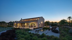 A modern house with a covered patio, a small pond, and surrounding greenery. - Villa Majoli 9 in Noto (Noto)