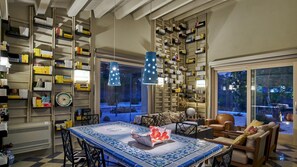 A spacious living room with a large tiled coffee table, a comfortable sofa, and a bookshelf filled with books.