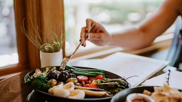 A person dining at a table with a variety of vegetables and a small bowl of sauce.