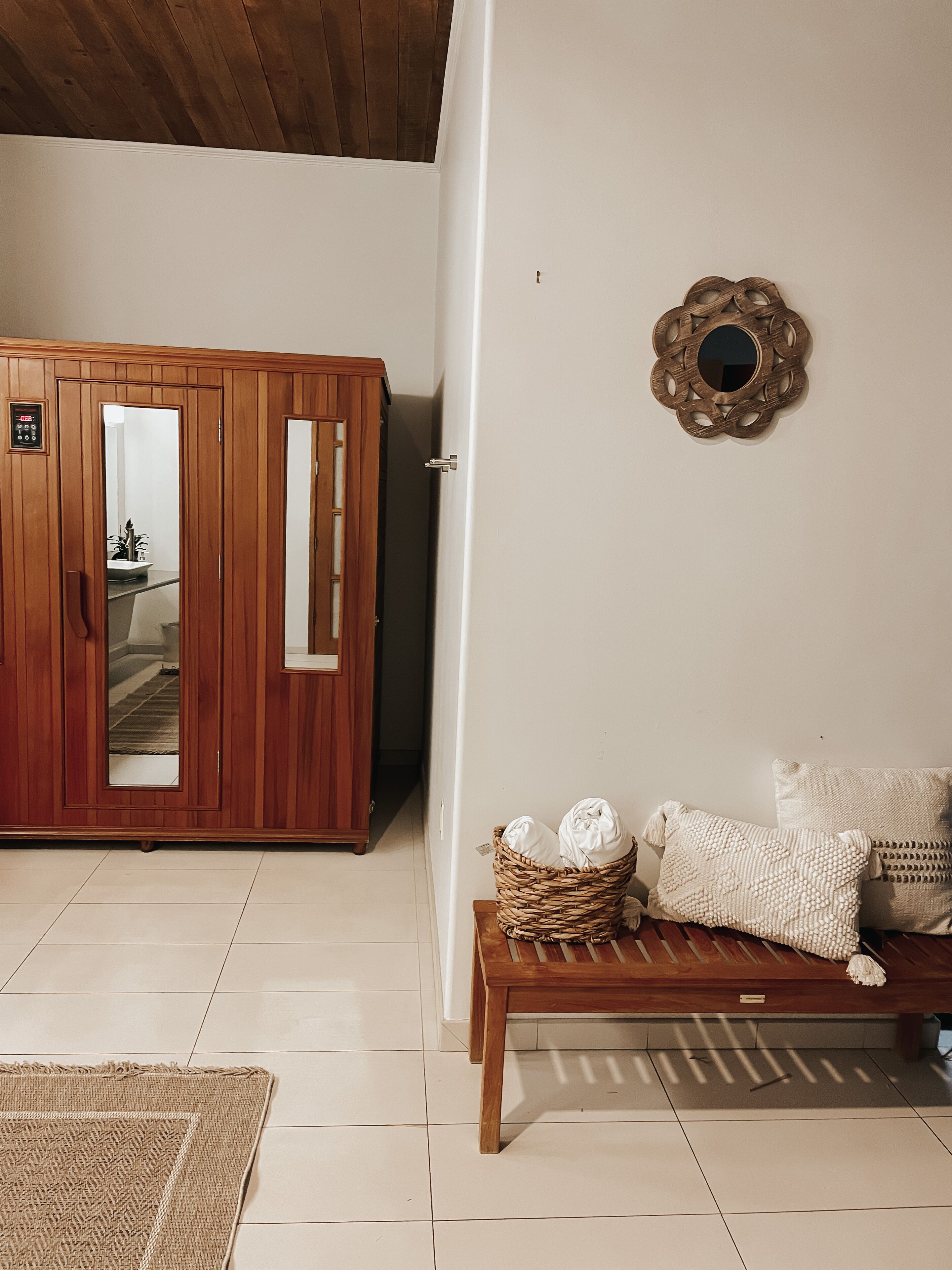 Een kamer met een houten garderobe, een bank met kussens en een decoratief wandobject.
