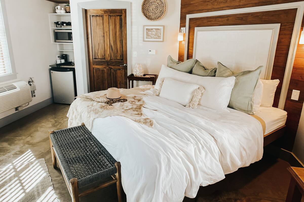 Un dormitorio con una cama grande, techo de madera y una mesita de noche pequeña.