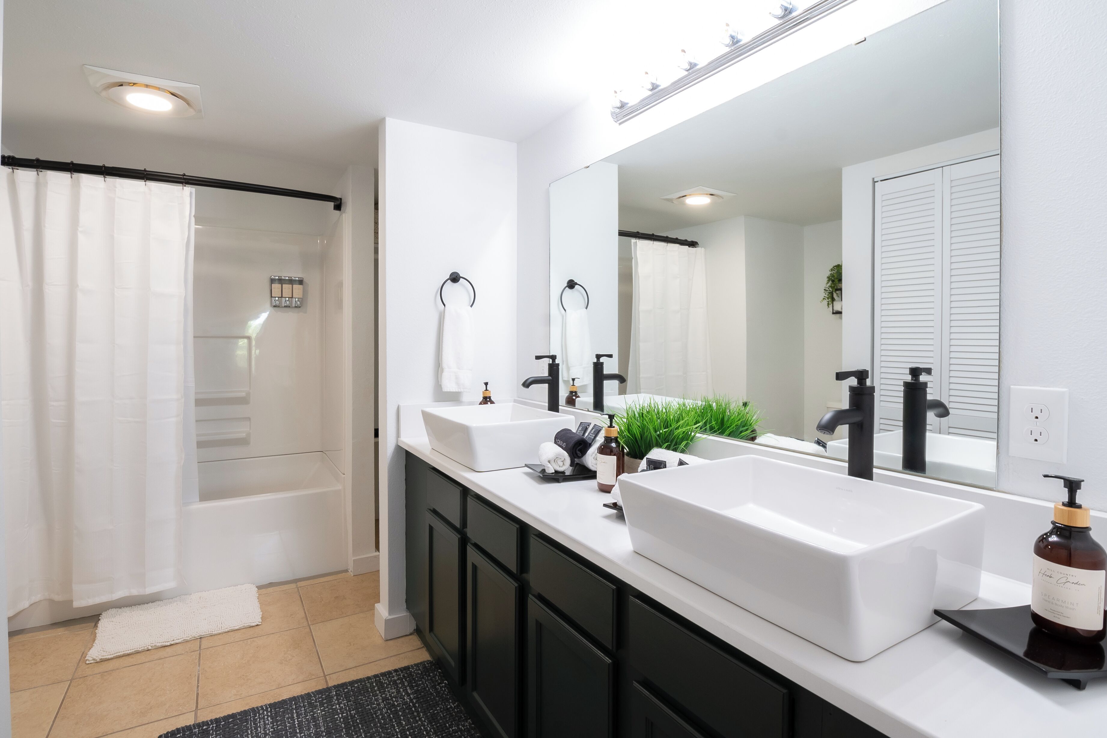 Un baño moderno con dos lavabos, un espejo grande y una zona de ducha.