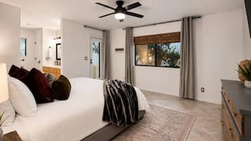 Una camera da letto moderna con un letto grande, una ventola a soffitto, vista sull'esterno e un comò in legno.