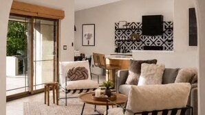 Un interior con ventilador de techo, sofá, sillón, mesa de centro y alfombra estampada.
