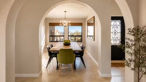 Un comedor con arco, una lámpara de araña, una mesa de madera y sillas.