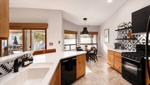 Una cocina moderna con una isla central, armarios de madera, horno empotrado y comedor con mesa y sillas.