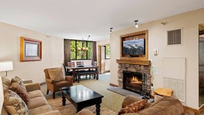 A living room with a fireplace, a dining area, and a TV mounted above the fireplace.