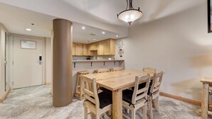 Ein Essbereich mit Holztisch und -stühlen, einer großen Säule und einer Küche im Hintergrund.