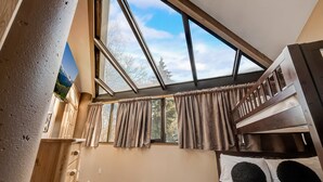 Ein Zimmer mit einem Oberlicht, einem Etagenbett und einer Holzkammer.