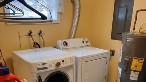 Zona de lavandería con lavadora, secadora y cestos de ropa apilados.