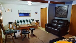 Una sala de estar con un sofá, un sillón de cuero, una mesa de madera y dos sillas.