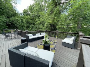 Une terrasse dotée de mobilier d’extérieur, notamment d’un canapé et de fauteuils, entourée d’une végétation luxuriante.