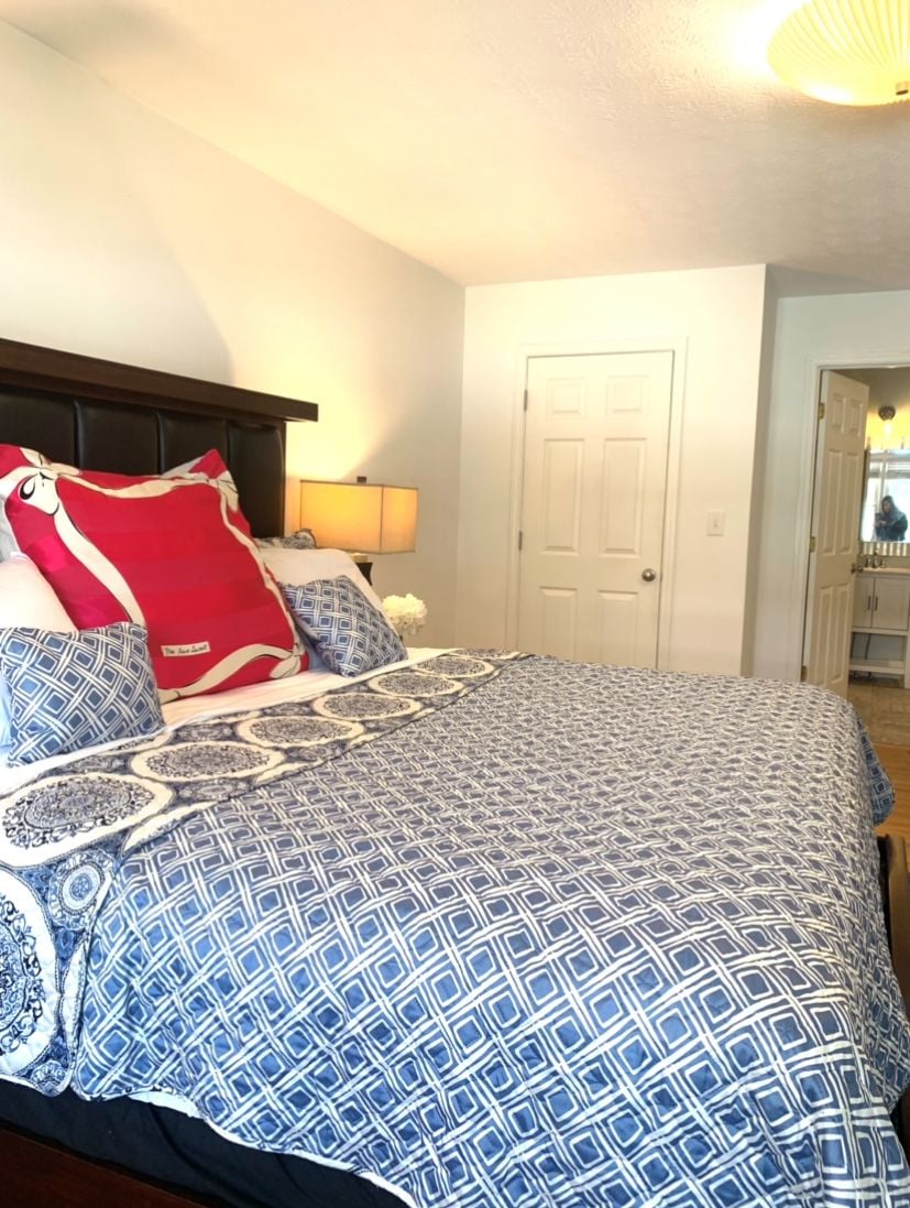 A bedroom with a bed, a nightstand, a lamp, and a door.
