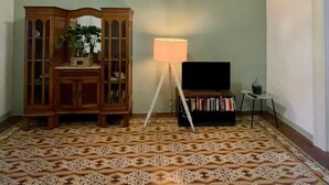 Ett rum med ett mönstrat golv, ett träskåp, en golvlampa och en tv.