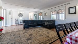 Amplia sala de estar con un sofá de cuero negro, un tapete estampado y un mantel a cuadros.
