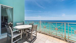 Ein Balkon mit Tisch und Stühlen mit Blick auf das türkisblaue Meer.