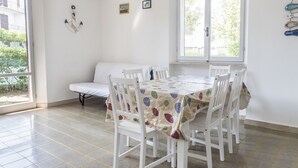 Et spiseområde med et bord, stole, en sofa og et vindue med udsigt.