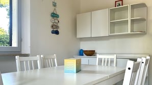 Spisebord med stole, et hvidt skab over og en dekorativ vægophængning.
