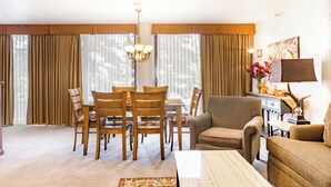 A living room with a dining area, featuring a chandelier, curtains, and a sofa. - Silver King 203 | 150 Yards to Lifts | Fireplace | Kitchen | End Unit | Mtn View | Pool & Hot Tub (Park City)