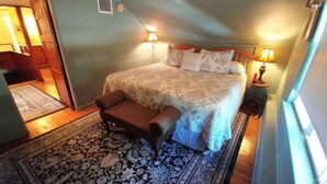 A bedroom with a large bed, a bench, and two bedside lamps. - Beautiful Historic Cottage, Hideaway (Mount Dora)