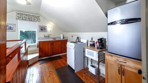 A compact kitchen with wooden cabinets, a stove, a microwave, and a refrigerator. - Beautiful Historic Cottage, Hideaway (Mount Dora)