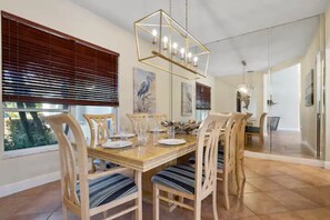 Un espace repas avec une table et des chaises en bois, un luminaire suspendu et des œuvres d’art accrochées aux murs.