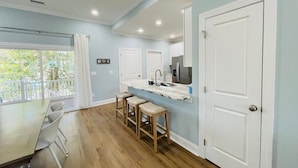 A modern kitchen with a marble countertop, wooden stools, and a view of the outdoors through a large window. - Fabulous 4 bedroom house in North Myrtle Beach (North Myrtle Beach)