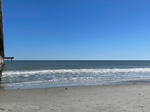 Ein Strand mit einem Steg, der sich ins Meer erstreckt.