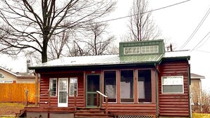 Une petite cabane en rondins d’un seul étage, avec un toit vert, portant le numéro 752, et dotée d’une véranda et d’une porte d’entrée.