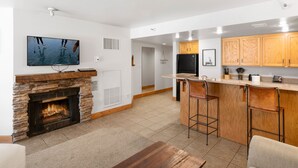 A modern kitchen with wooden cabinets, a built-in stove, and a bar area with stools.