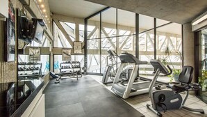 A modern gym with treadmills, elliptical machines, and weight racks.