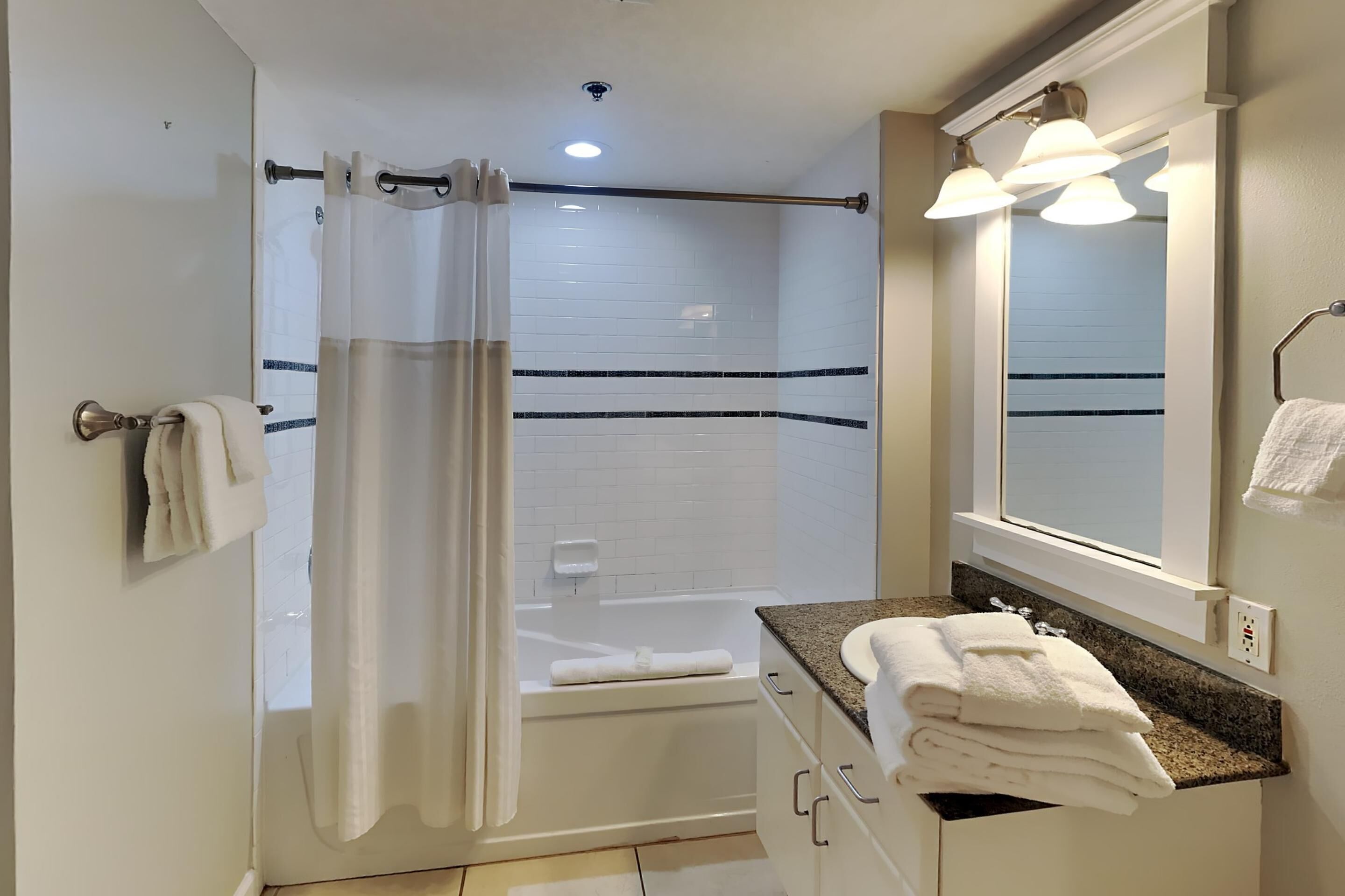 Un baño con ducha, bañera, tocador con espejo y un perchero para toallas.