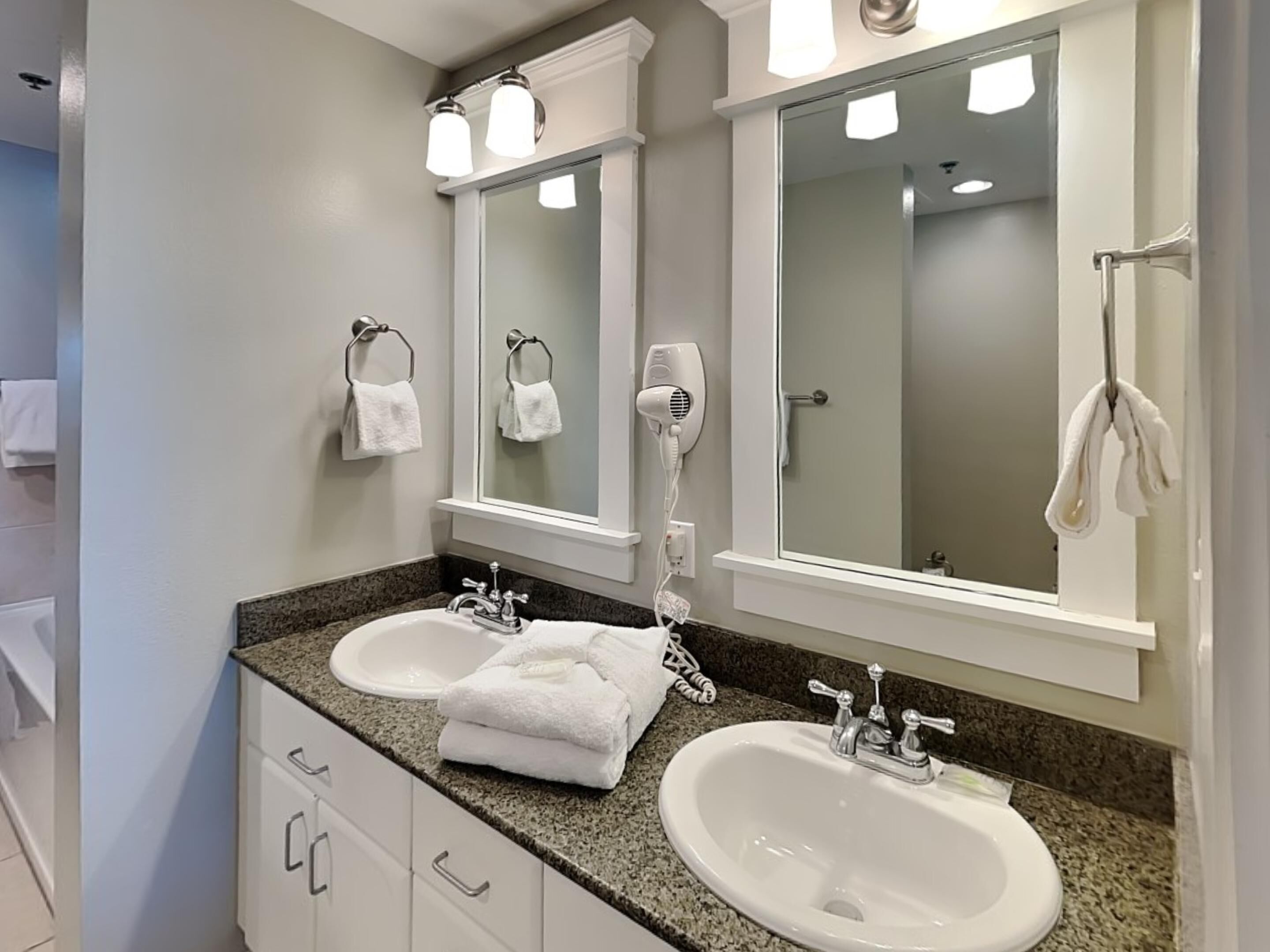 Un baño con dos lavamanos, un secador de pelo y un perchero para toallas.